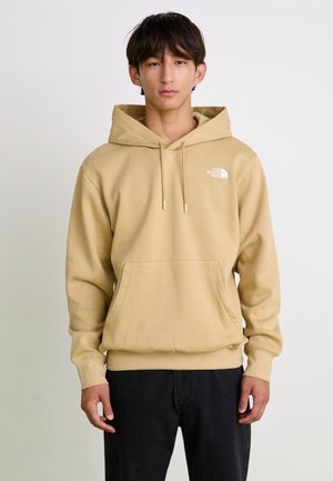 Sudadera beige con capucha, bolsillo frontal, cordones y un pequeño logo blanco en el lado izquierdo del pecho; fabricada en tejido suave y con puños de canalé.