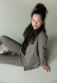 Geverifieerd grijs pak met een getailleerde blazer en gepaste broek. Gedragen over een donkere top, gecombineerd met lichtgekleurde enkellaarsjes. Soepele textuur.