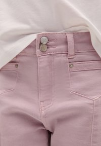 Rosa Jeans aus Denim mit hoher Taille, ausgestattet mit zwei Metallknöpfen, Eingrifftaschen und detaillierten Nähten entlang der Nähte.