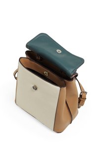 Torebka skórzana w dwóch kolorach z beżową kieszenią z przodu, turkusowym klapkiem i brązowymi bokami, otwarta, aby ujawnić wnętrze z przegródkami oraz regulowanym paskiem.