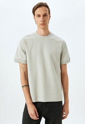 Jasnoszary t-shirt z krótkim rękawem, z okrągłym dekoltem, wykonany z gładkiego materiału. Posiada prosty krój i minimalne detale przeszycia.