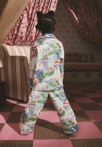 Värikäs kuviollinen yöpaitasetti, jossa on hurmaavia kohtauksia puista, taloista ja hahmoista. Puuvillakangasta, pitkät hihat ja housut.