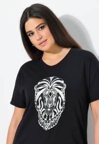 Czarny t-shirt z dużym srebrnym wzorem lwa złożonym z złożonych wzorów geometrycznych. Krótkie rękawy i okrągły dekolt.