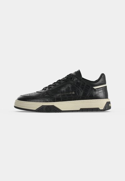 Baskets basses noires avec texture crocodile, semelle beige, lacets et logo "roberto cavalli" embossé sur le côté.