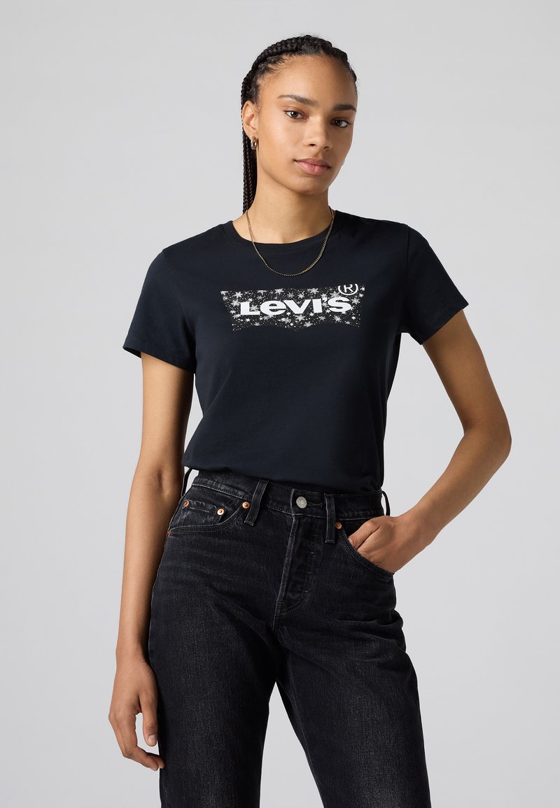 Black cotton t-shirt featuring a white Levi's graphic logo; paired with high-waisted black denim jeans; minimalistic design and smooth texture.