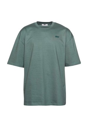 Camiseta de algodón verde con mangas cortas, cuello redondo y el texto "DEF" impreso en verde oscuro en la zona del pecho izquierdo.