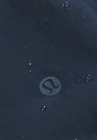 Námořnická voděodolná tkanina s texturovaným povrchem, na kterém jsou vodní kapky a embosované kruhové logo v dolním pravém rohu.