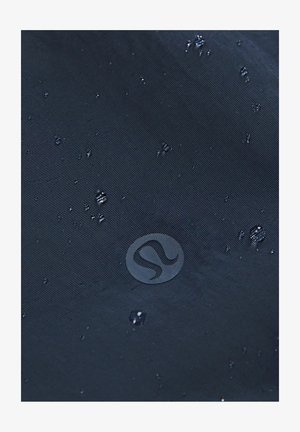 Marineblauwe waterdichte stof met een gestructureerde afwerking, met waterdruppels en een cirkelvormig logo dat op de rechteronderhoek is geperst.