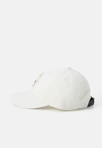 Casquette en coton blanc avec sangle noire ajustable, visière incurvée et logo brodé à l'avant. Comprend six œillets de ventilation.