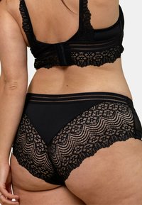 Ensemble de lingerie noire, comprenant un soutien-gorge en dentelle avec des bretelles réglables et une culotte assortie, mettant en valeur des motifs en dentelle intricate et un tissu doux.