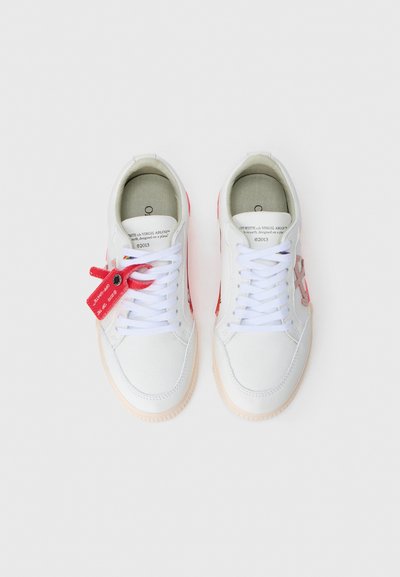 Adidași din piele albă cu accente roz, șireturi plate albe și o etichetă de marcă roșie. Talpă din cauciuc texturat, design minimalist și căptușeală interioară moale.