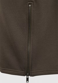 Olivgrön zip-up jacka med en slät tygtextur och en central dragkedja med en metalldragning. Inga extra mönster eller accenter.