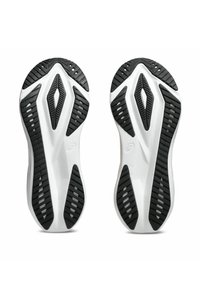 Semelles de chaussures de sport avec une base blanche flexible et un revêtement en caoutchouc noir présentant des rainures diagonales et des motifs en diamant pour une adhérence.