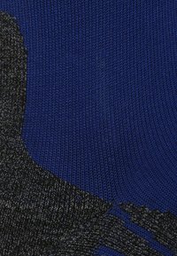 Tejido de punto azul con un patrón texturizado en negro. El diseño incluye tonos variados y detalles de tejido intrincados.