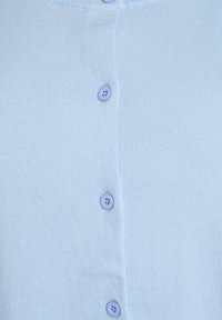 Svijetloplavi kardigan od mekanog, pletenog materijala s rebrastom teksturom. Ima pet ljubičastih gumba sprijeda i okrugli izrez ovratnika.