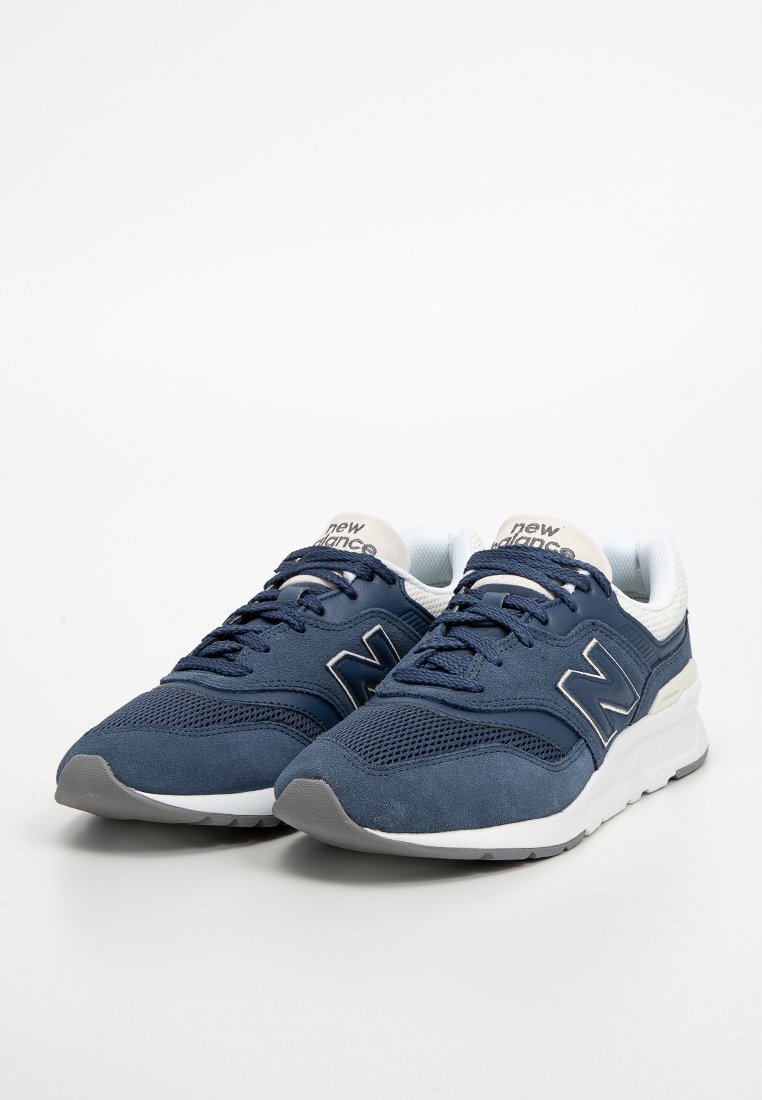 Marineblauwe sportschoenen met een mesh bovenkant, suède accenten, witte zool en grijze rubberen buitenzool; voorzien van veters en een logo-embleem.
