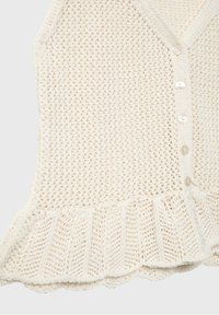 Gilet tricoté couleur crème avec fermeture boutonnée devant et ourlet à volants, présentant un motif texturé à maille ouverte.