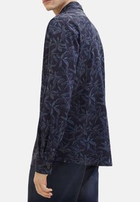 Navyblaues Langarmhemd mit einem Blattmuster in Blau- und Blautönen, ausgestattet mit einem Knopfmanschette und einem klassischen Kragen. Aus einem Baumwollgemisch.