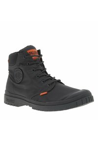 Black waterproof boot with orange accents, round logo patch, lace-up design, and a rugged rubber sole featuring textured grip pattern.