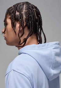 Hoodie azul claro com cordão, usado com um penteado texturizado de várias tranças. Vista de perto do lado, mostrando os detalhes.