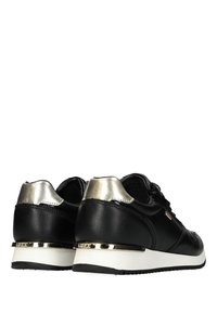 Černé kožené tenisky s metalicky stříbrnými akcenty, křivkový tvar, gumová podrážka a šněrovací design. Zlaté logo poblíž paty.