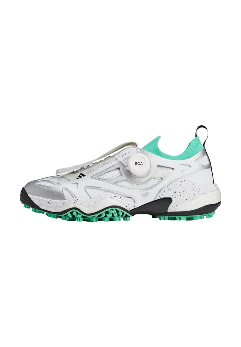 Zapatilla deportiva blanca con un diseño texturizado, acentos en verde menta y un mecanismo de ajuste de cordones circular. Presenta una suela negra con tracción.
