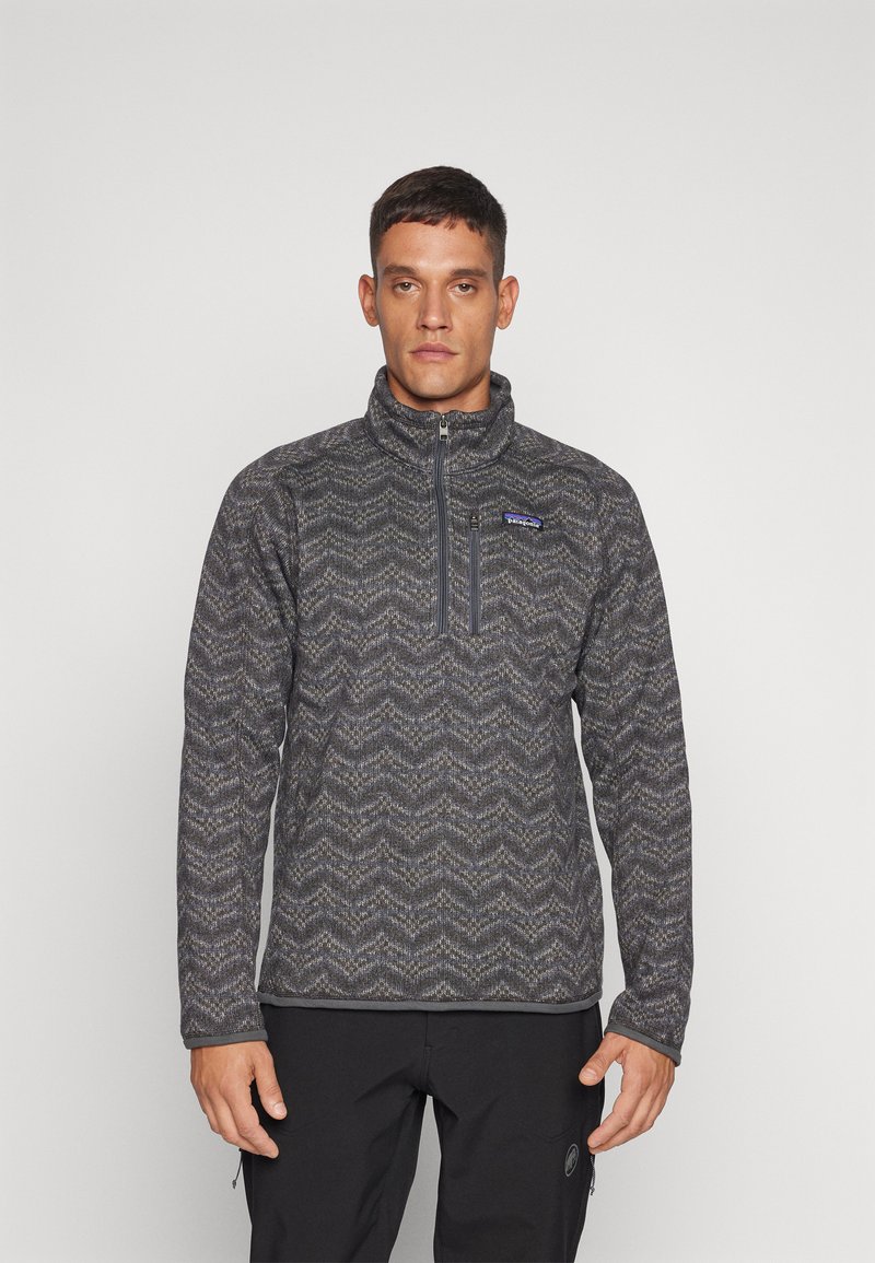 Fleece pullover with a half-zip, featuring a gray zigzag pattern, high collar, and chest pocket. Textured fabric with a soft finish.