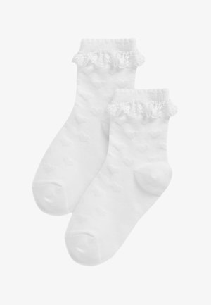 Chaussettes blanches à la cheville avec motifs texturés en forme de cœur et bordure à volants en dentelle aux poignets.