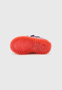 Chaussures Geox avec une semelle en caoutchouc rouge texturé, présentant des rainures et des motifs pour l'adhérence. Matière supérieure en bleu avec fermeture à sangle ajustable.