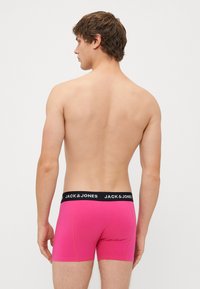 Moške roza bombažne bokserice s črnim pasom. Pas vsebuje besedilo "JACK & JONES" in zasnovo tesnega prileganja.