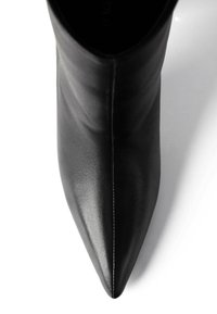 Botine negre din piele cu vârf ascuțit, textura netedă, cu un tiv înalt și detalii minime de coasere, plasate pe un fundal alb.