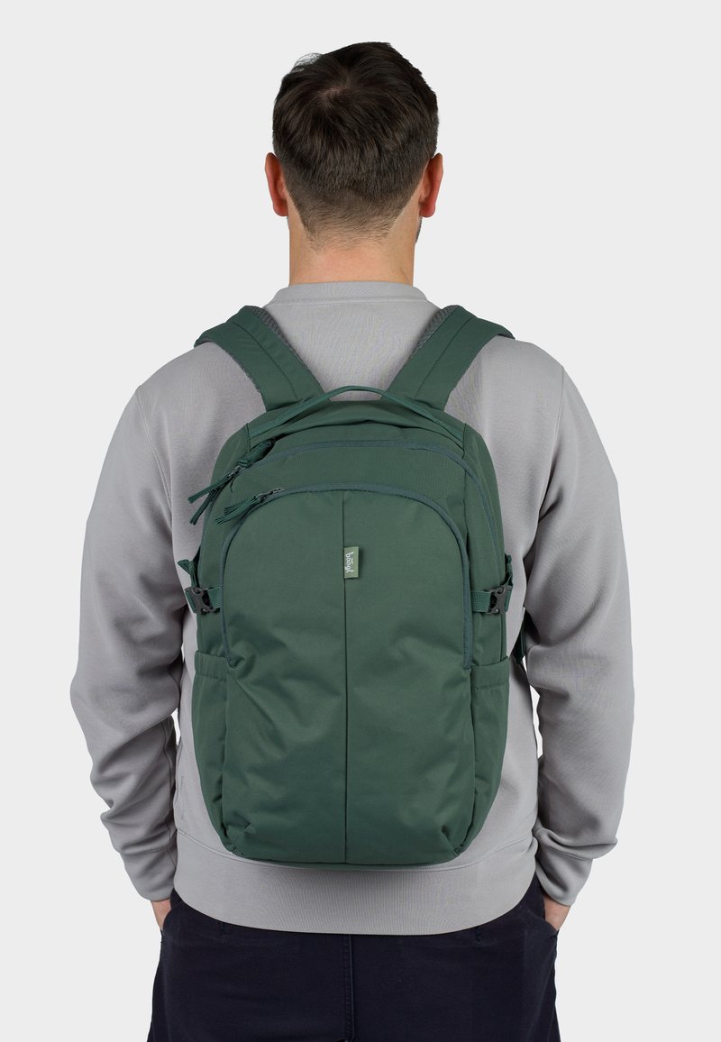 Zelený batoh s nastavitelnými popruhy, několika zipovými kapsami, hladkým textilním povrchem a nášivkou loga na přední straně.
