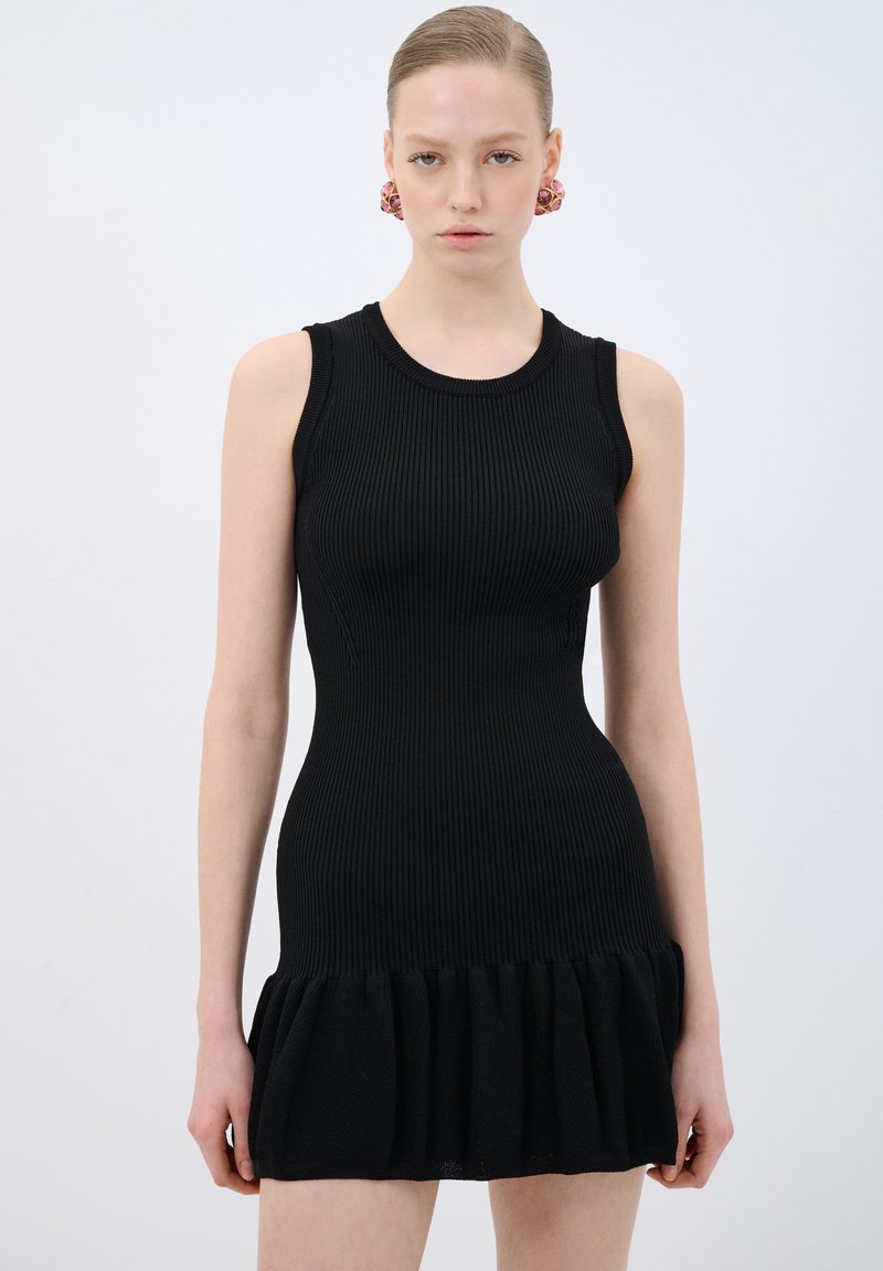 Abito a maglia nera a coste con corpetto aderente e orlo a balze svasato. Design senza maniche e scollatura rotonda, con una texture liscia.