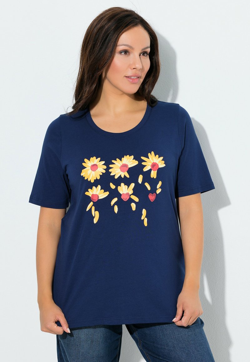 Maglietta blu navy con scollo a girocollo, caratterizzata da una stampa floreale di margherite gialle e cuori rossi. Maniche corte e vestibilità comoda.