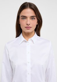 Witte lange mouwen button-up shirt met kraag, gemaakt van een gladde stof, met parelknoopjes en een getailleerd silhouet.