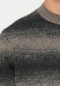 Gray and black gradient patterned sweater with a ribbed round neck, featuring soft, fuzzy texture and a relaxed fit.