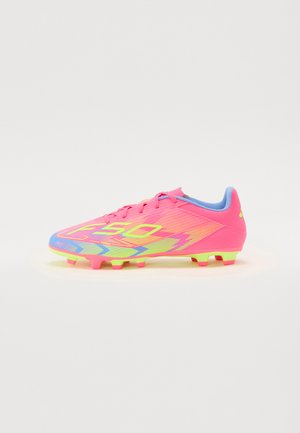 Bottes de football rose vif avec des accents jaune-vert, en matériau synthétique lisse, et un motif de grip texturé sur la semelle.