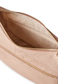 Interno di una borsa rosa pallido testurizzata con una cerniera metallica dorata. Presenta una piccola tasca con cerniera e un motivo sottile sulla fodera.