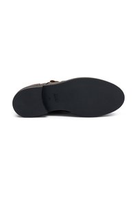 Scarpa in pelle marrone con un design testurizzato, dotata di una morbida suola in gomma nera, dettagli cuciti e un branding minimale sulla suola.