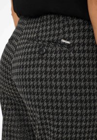 Gestrikte zwart-witte houndstooth broek met een achterzak met knoopsluiting en een klein zilveren accentdetail.