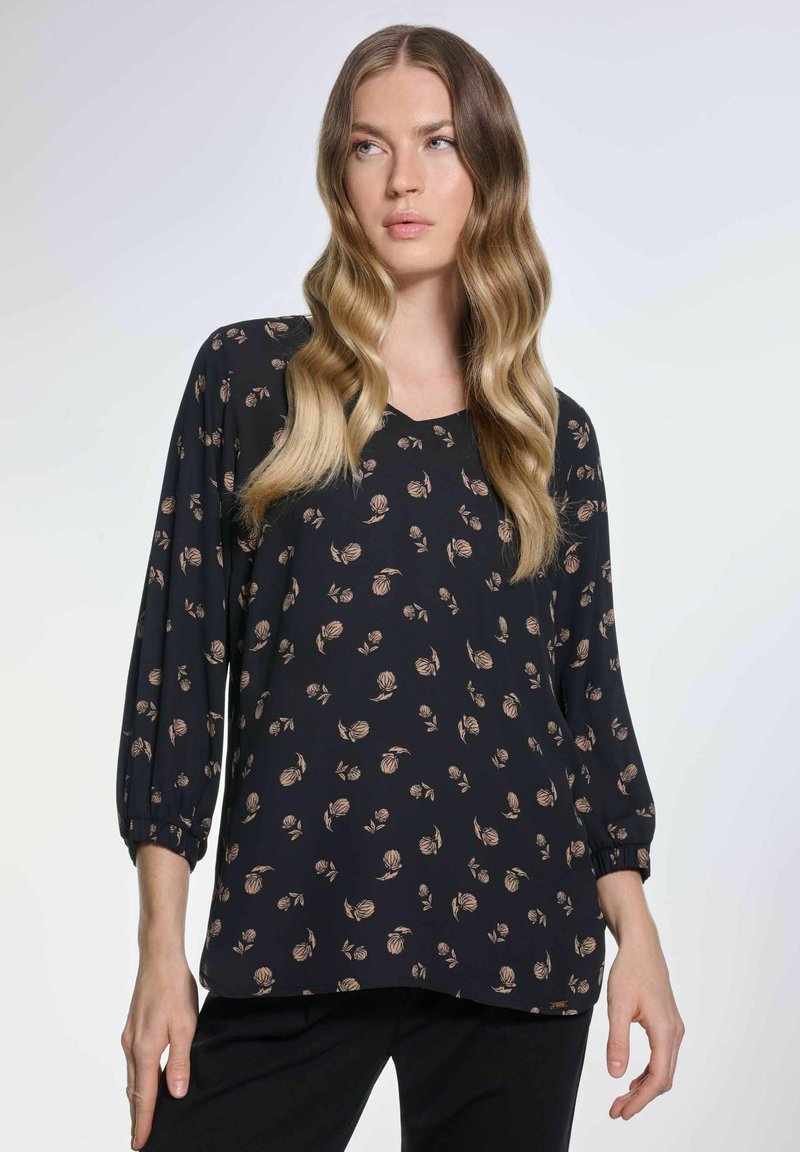 Granatowa bluzka z trzema ćwiartkami rękawów, zdobiona kwiecistym wzorem w kremowych i brązowych odcieniach. Lekki materiał o luźnym kroju i okrągłym dekolcie.