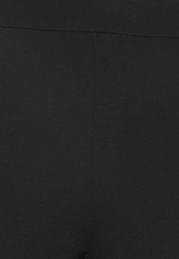 Czarne legginsy wykonane z elastycznego materiału, charakteryzujące się gładką teksturą, wysokim stanem i klasyczną sylwetką. Brak widocznych wzorów lub akcentów.