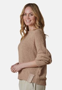 Hellbrauner Strickpullover mit strukturiertem Finish, langen Ärmeln und geripptem Saum. Verfügt über ein seitliches Etikett mit Schriftzug.