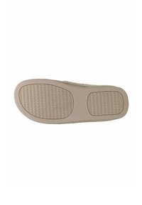 Sole of beige slip-on shoe showing textured rubber grip areas on heel and ball for traction and comfort.