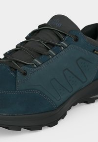 Σκούρο πετρόλ πεζοπορικό παπούτσι με μαύρες λεπτομέρειες, χοντρή σόλα με πέλμα, μαύρα κορδόνια και ετικέτα Gore-Tex στην πλευρική επιφάνεια.