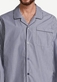 Navy- und weiß gestreiftes Schlafshirt aus weichem Stoff, mit einem Notch-Kragen, durchgehender Knopfleiste und einer einzelnen Brusttasche mit Streifen.
