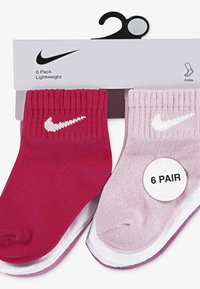 Κάλτσες αστραγάλου Nike, συσκευασία 6 τεμαχίων· αποχρώσεις περιλαμβάνουν σκούρο ροζ και ανοιχτό ροζ· ριγωτή υφή· διαθέτουν λευκό λογότυπο· συσκευασμένες με κυκλική ετικέτα.
