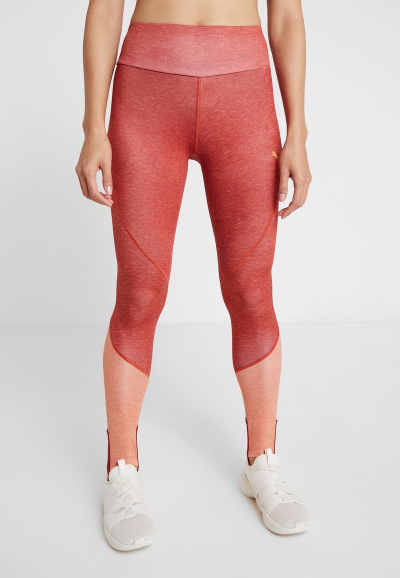 Leggings de sport rouges et dégradés d'orange clair avec une taille haute, un tissu texturé et des fermetures éclair aux chevilles pour faciliter l'enfilage.