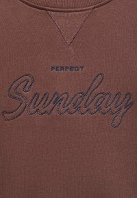 Rjav sweatshirt z vezenim napisom "PERFECT Sunday" v temno modri barvi, izdelan iz mehke, teksturirane tkanine in s krojnim izrezom.