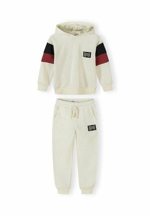 Sæt med cremefarvet hættetrøje og joggingbukser med sorte og mørkerøde striber på ærmerne samt "Unlimited Collective" tekstpatches på bryst og lår.